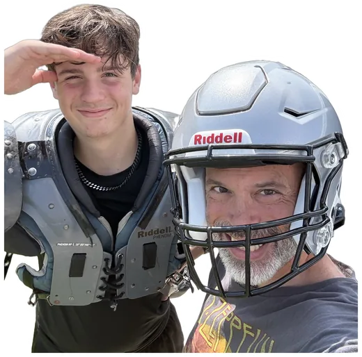 Adam in his son's football helmet, his son in shoulder pads